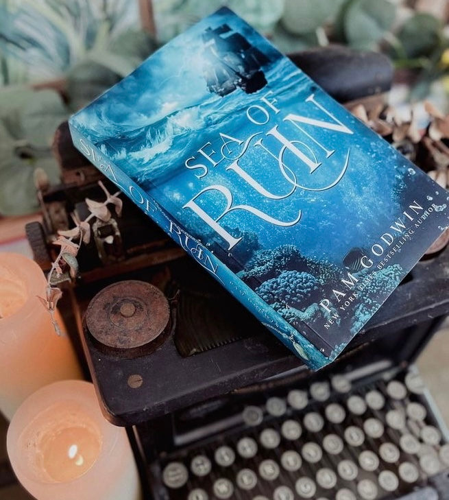 Sea of Ruin special edition cover by Pam Godwin with candles, leaves and a typewriter in the background.